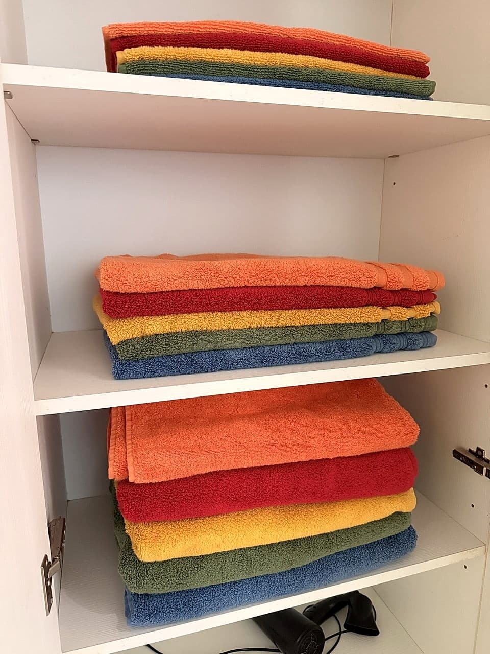 Un secondo armadio in corridoio appena fuori dal bagno, con pile aggiuntive di asciugamani colorati su tre ripiani