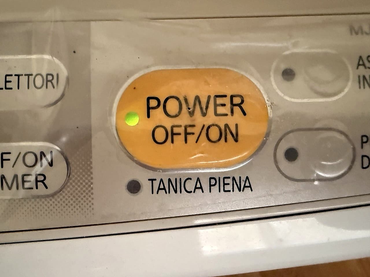 Primo piano del pannello del deumidificatore con il tasto POWER OFF/ON giallo e il piccolo led verde acceso all'interno · indicatore TANICA PIENA spento