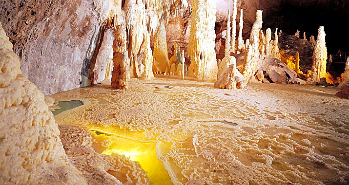 Sala del Laghetto Cristallizzato nelle Grotte di Frasassi · stalattiti, stalagmiti, riflesso dorato dell'acqua del laghetto sotterraneo
